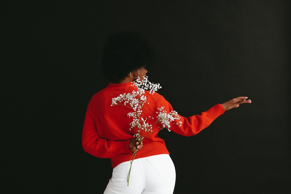 Back view of sensual black woman in white denim and white red sweater holding Gypsophila flower behi